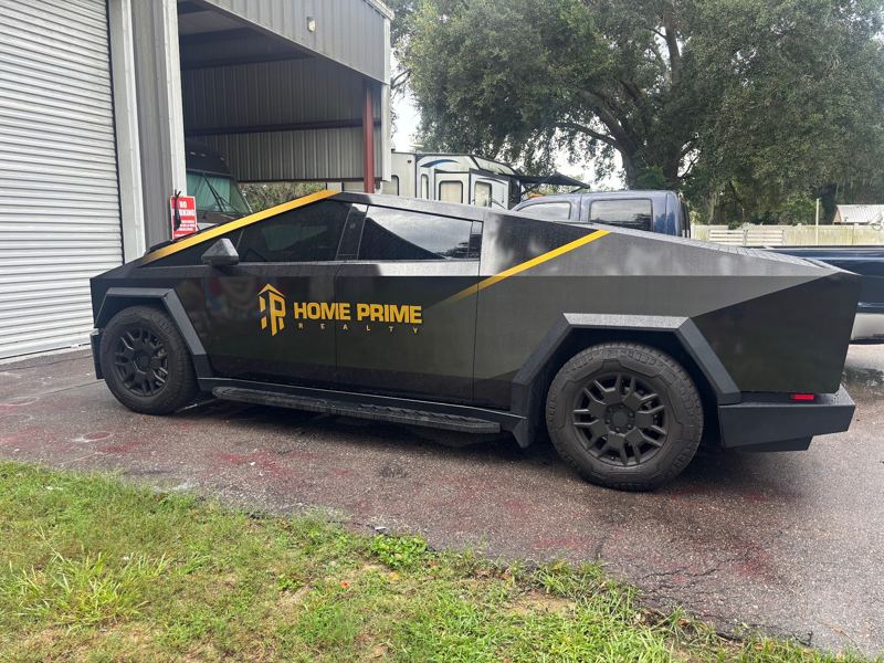 Dark Tesla Cybertruck with gold logo and pinstripe accents