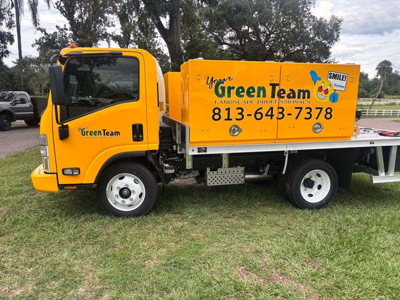 Yellow Isuzu work truck with landscaping company graphics