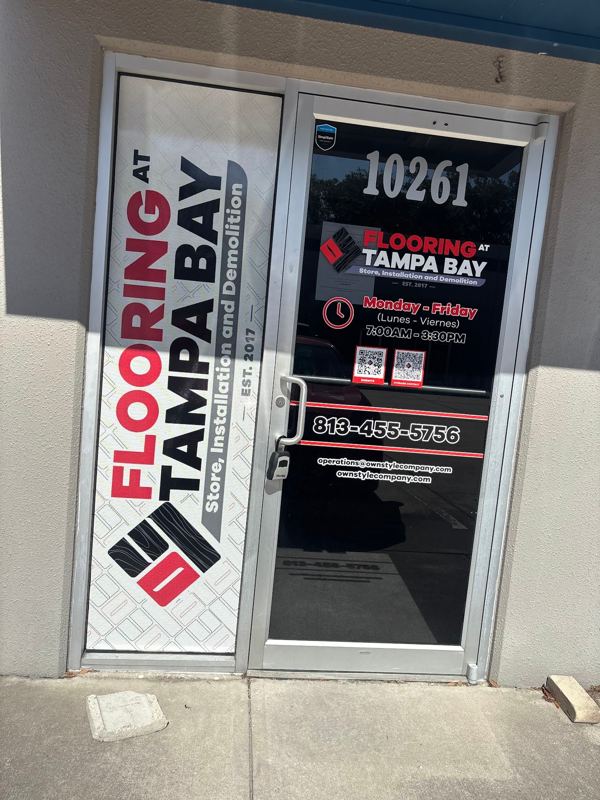 Storefront glass doors with a flooring company's logo and contact graphics