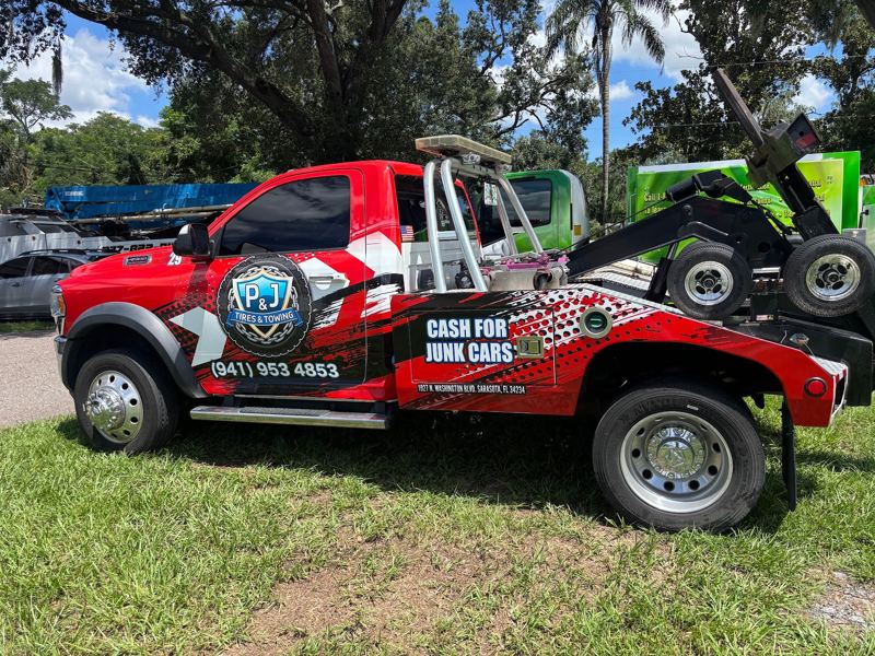 Red wrecker tow truck with printed graphics for a junk car buyer